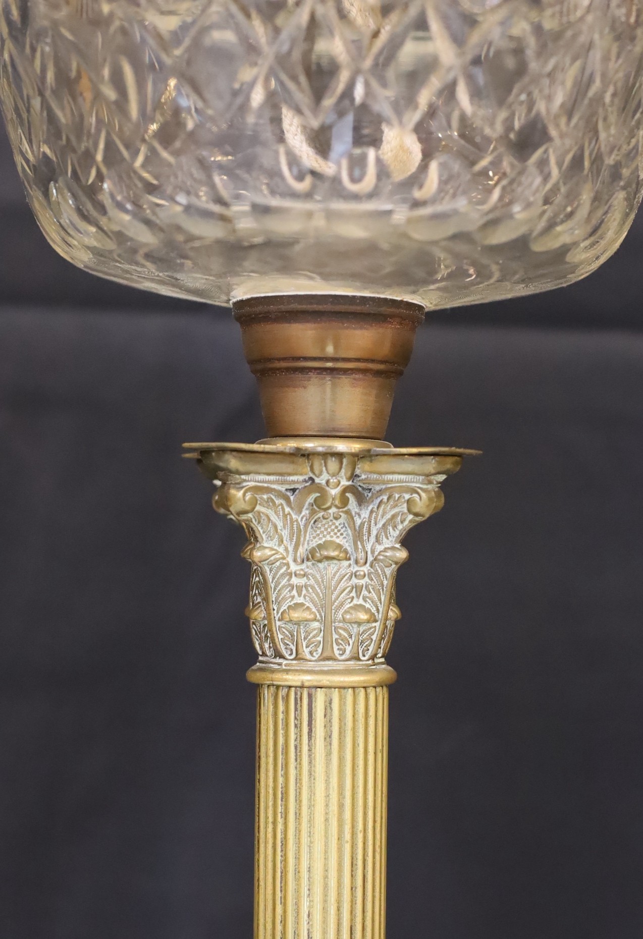 An Edwardian brass Corinthian column oil lamp with cut glass reservoir, improved duplex mechanism, etched globe and flue, height overall 85cm